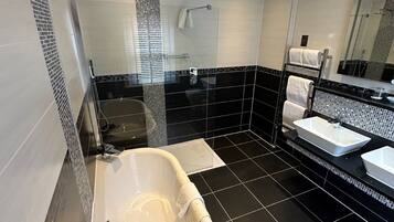A modern bathroom with a freestanding bathtub, a glass shower enclosure, and a vanity with a large mirror.