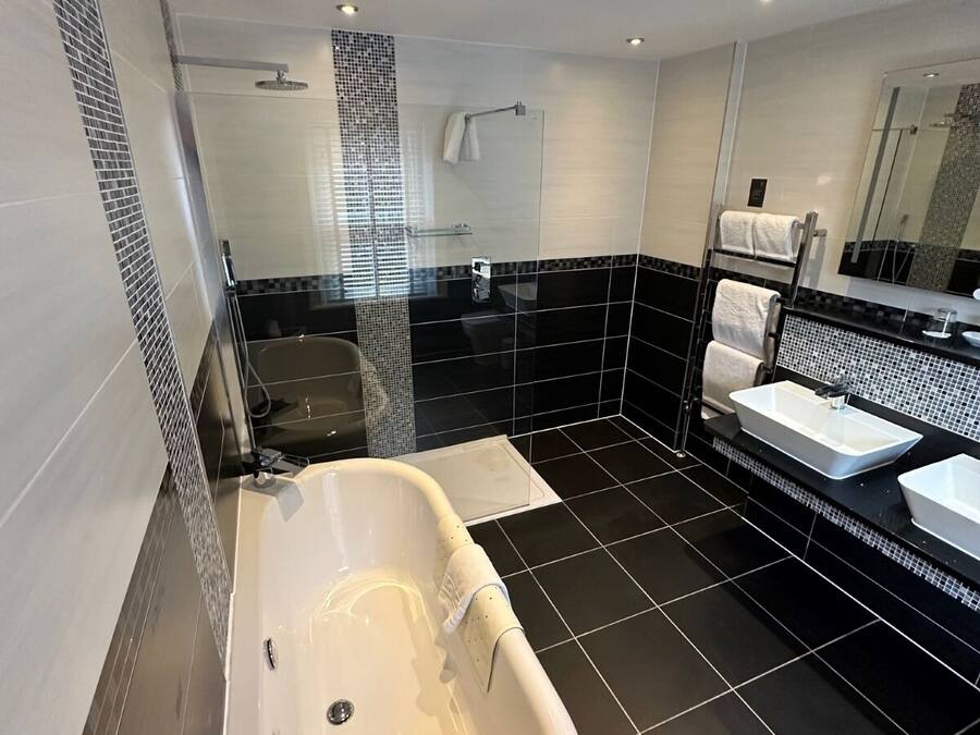 A modern bathroom with a freestanding bathtub, a glass shower enclosure, and a vanity with a large mirror.