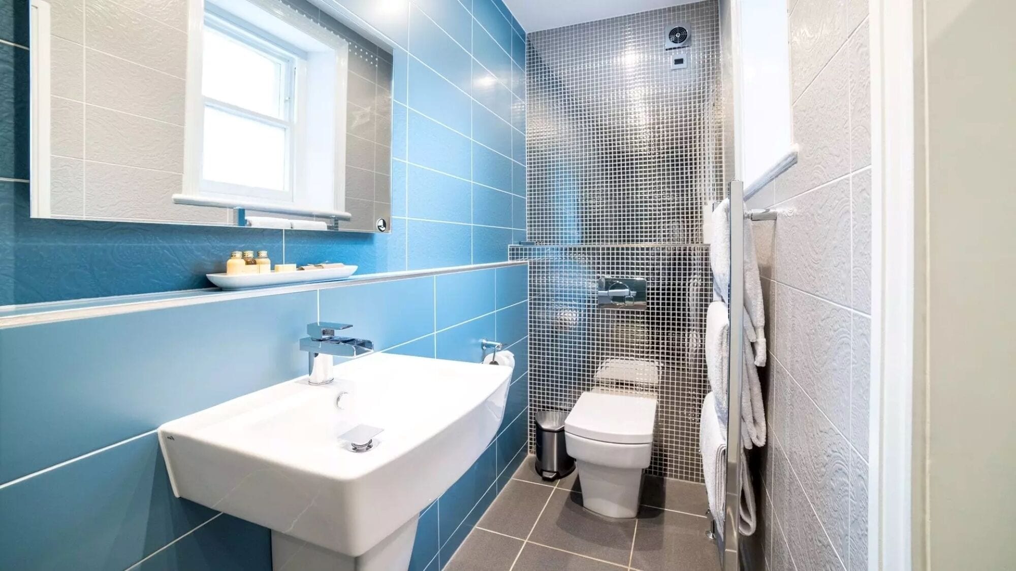 Un baño moderno con un lavamanos blanco, un inodoro y una zona de ducha.