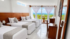A hotel room with three beds, a wooden headboard, a dining table, and a view of the ocean. - Hotel La Casa de Judy (Puerto Ayora)