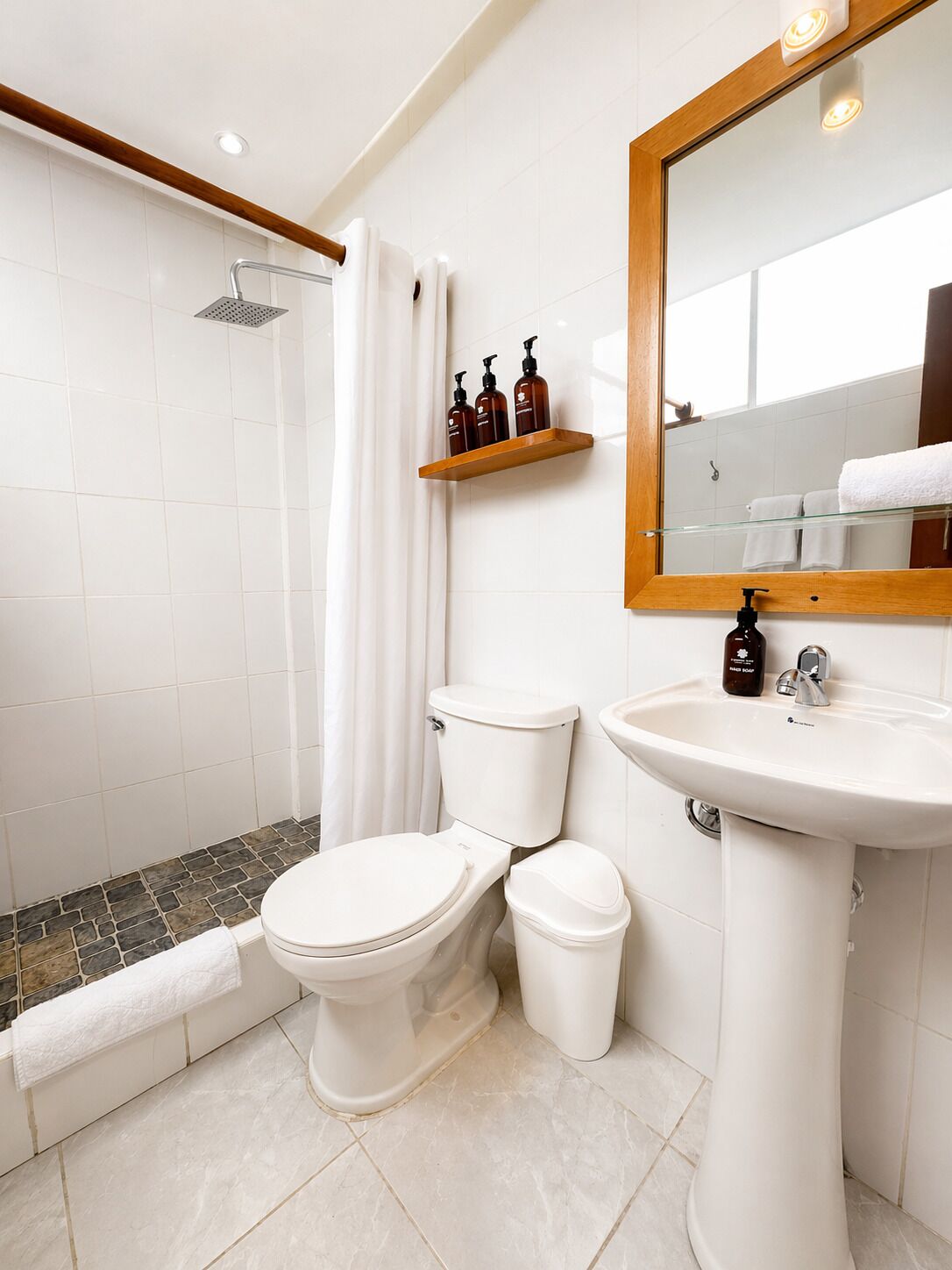 Une salle de bain équipée d’une douche, de toilettes, d’un lavabo et d’un miroir.