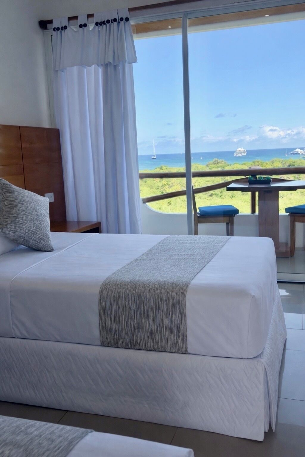 Un dormitorio con cama, vista al océano y balcón con mesa y sillas.