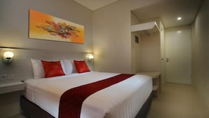 A hotel room with a bed, bedside tables, a painting, and a door. - The Rinaya Canggu (Tibubeneng)