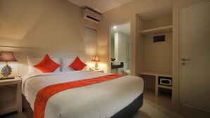 A hotel room with a bed, bedside lamps, a nightstand, a wardrobe, and an air conditioning unit. - The Rinaya Canggu (Tibubeneng)