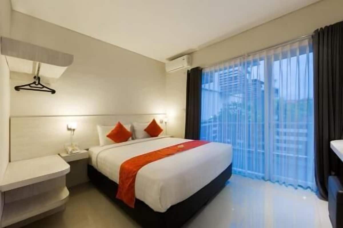 A hotel room with a bed, bedside tables, a hanging light, and a window with curtains.