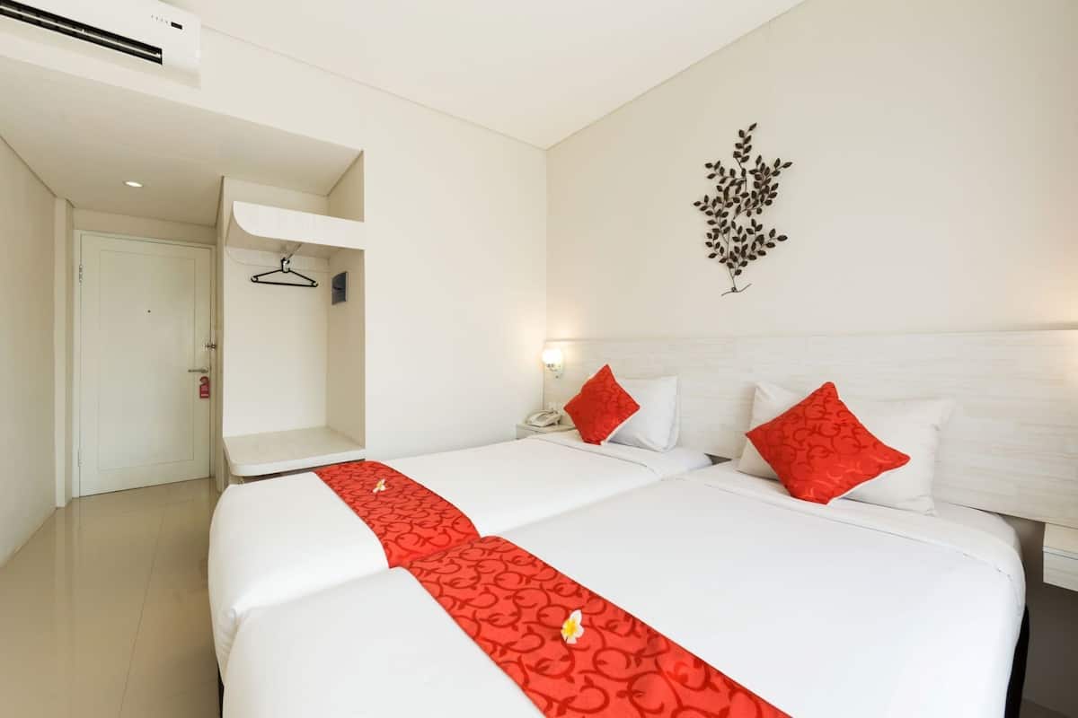 A hotel room with a bed, a bedside table, a wall-mounted phone, and a decorative wall piece.