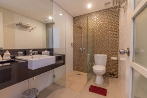 Et moderne badeværelse med et stort spejl, to håndvaske, et toilet og en bruseplads.