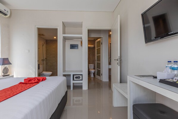 A hotel room with a bed, a desk, a TV, and a bathroom visible through an open door. - The Rinaya Canggu (Tibubeneng)