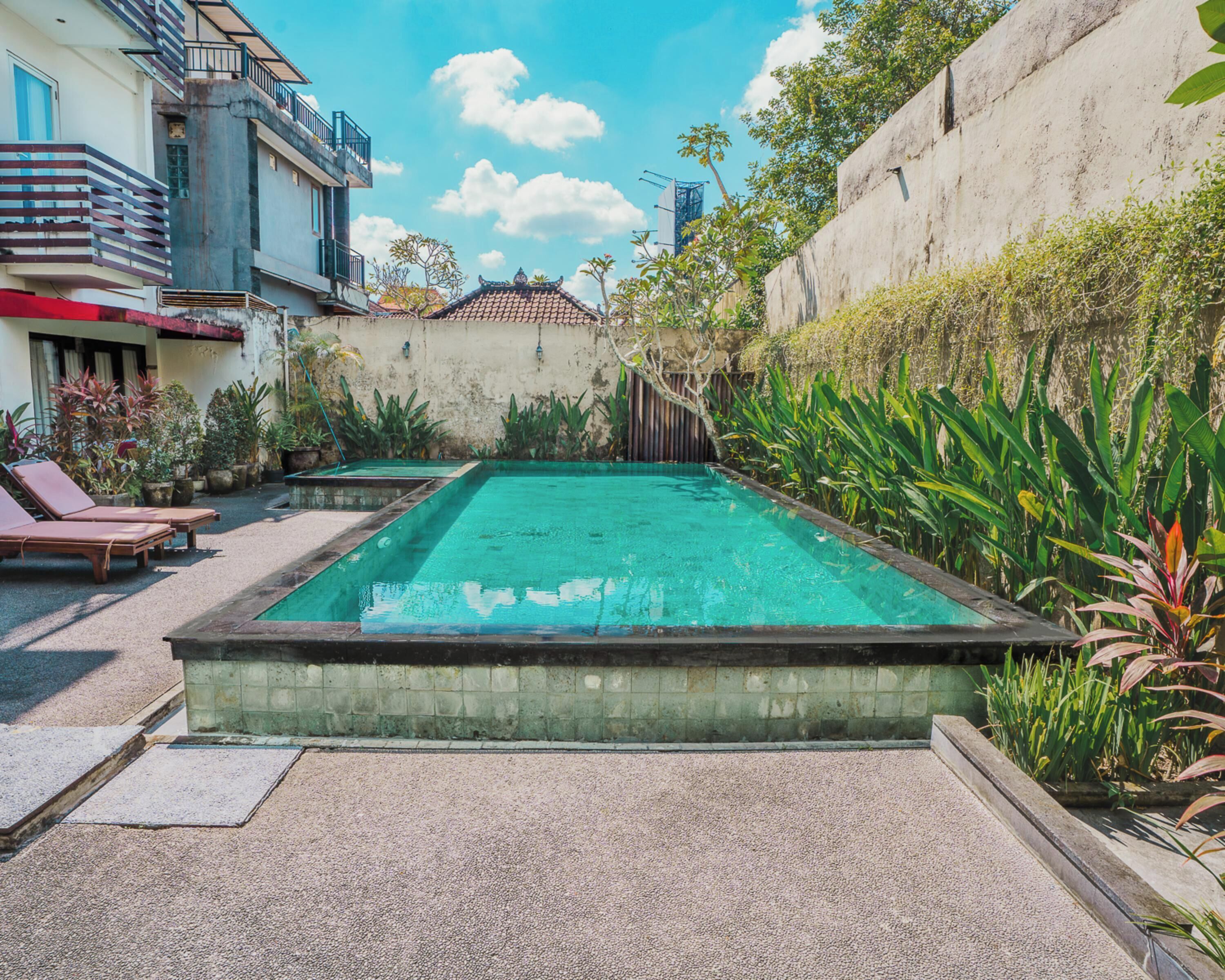A rectangular swimming pool with a tiled edge, surrounded by a gravel area.