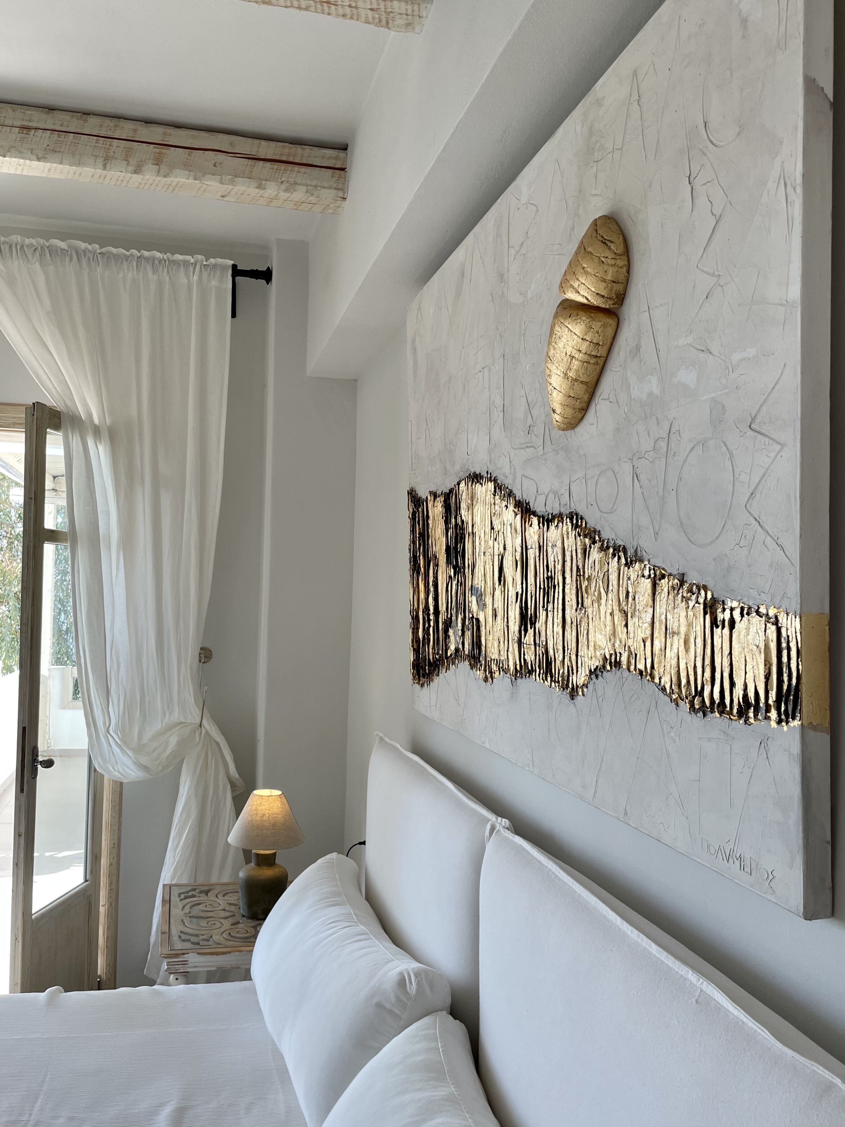 Une chambre à coucher comprenant un lit, une table de chevet, une lampe, une œuvre d’art accrochée au mur et une fenêtre avec des rideaux.