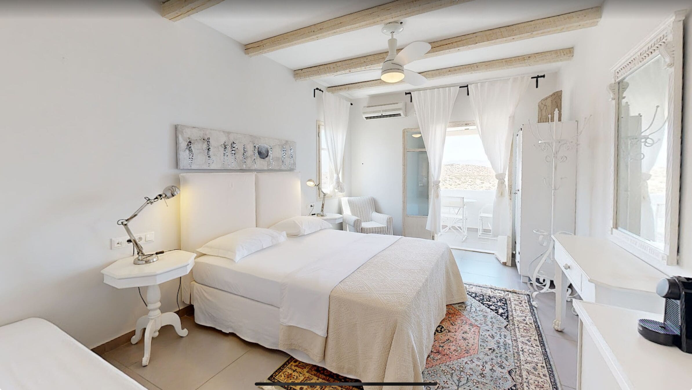 A bedroom with a large bed, bedside tables, a chair, a desk, and a mirror.