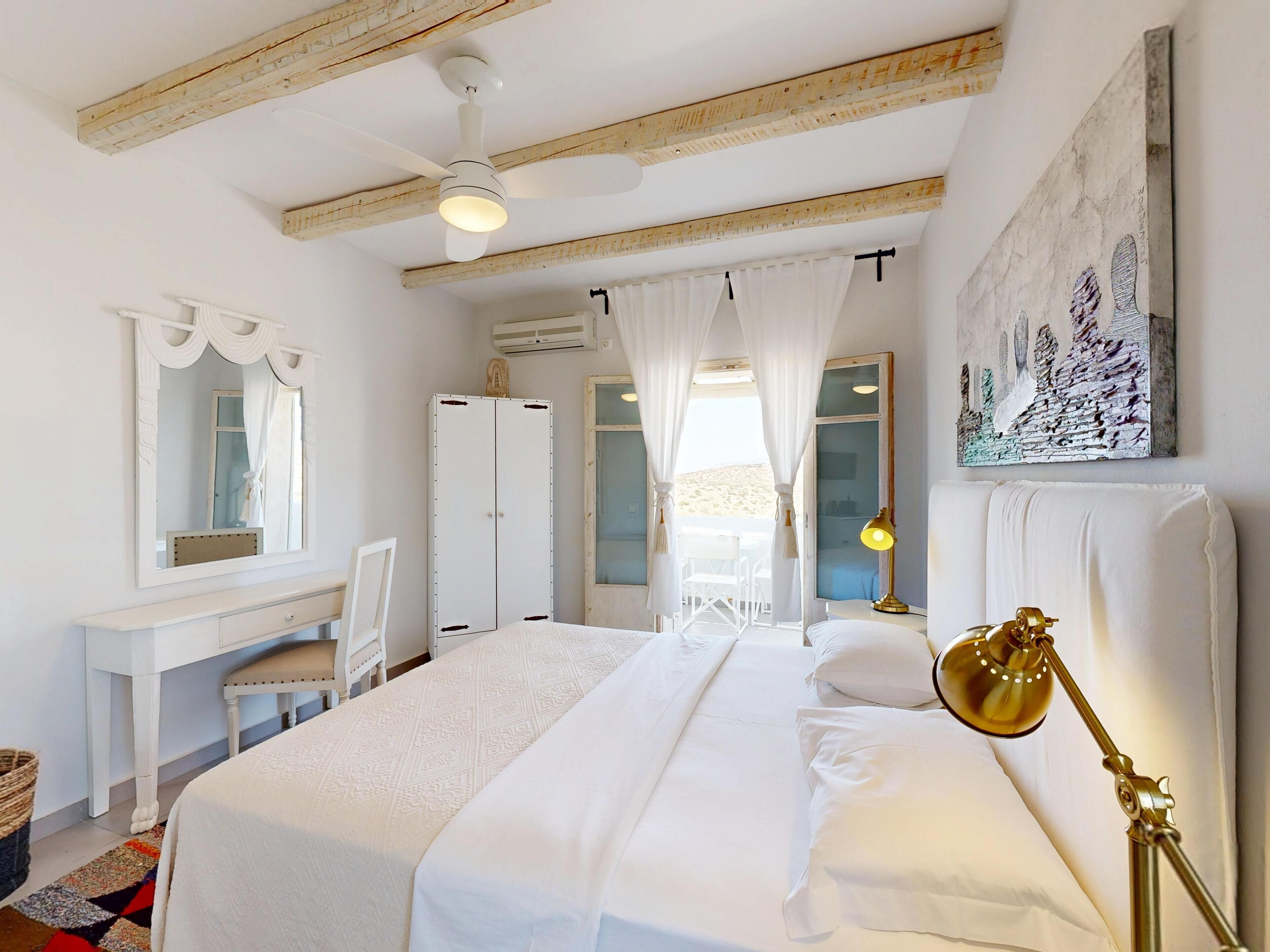 A bedroom with a bed, a desk, a chair, a wardrobe, and a painting on the wall.