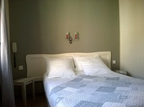 A bedroom with a bed, two bedside tables, a wall-mounted light fixture, and a telephone. - Hôtel Sainte Anne (Les Salles-sur-Verdon)