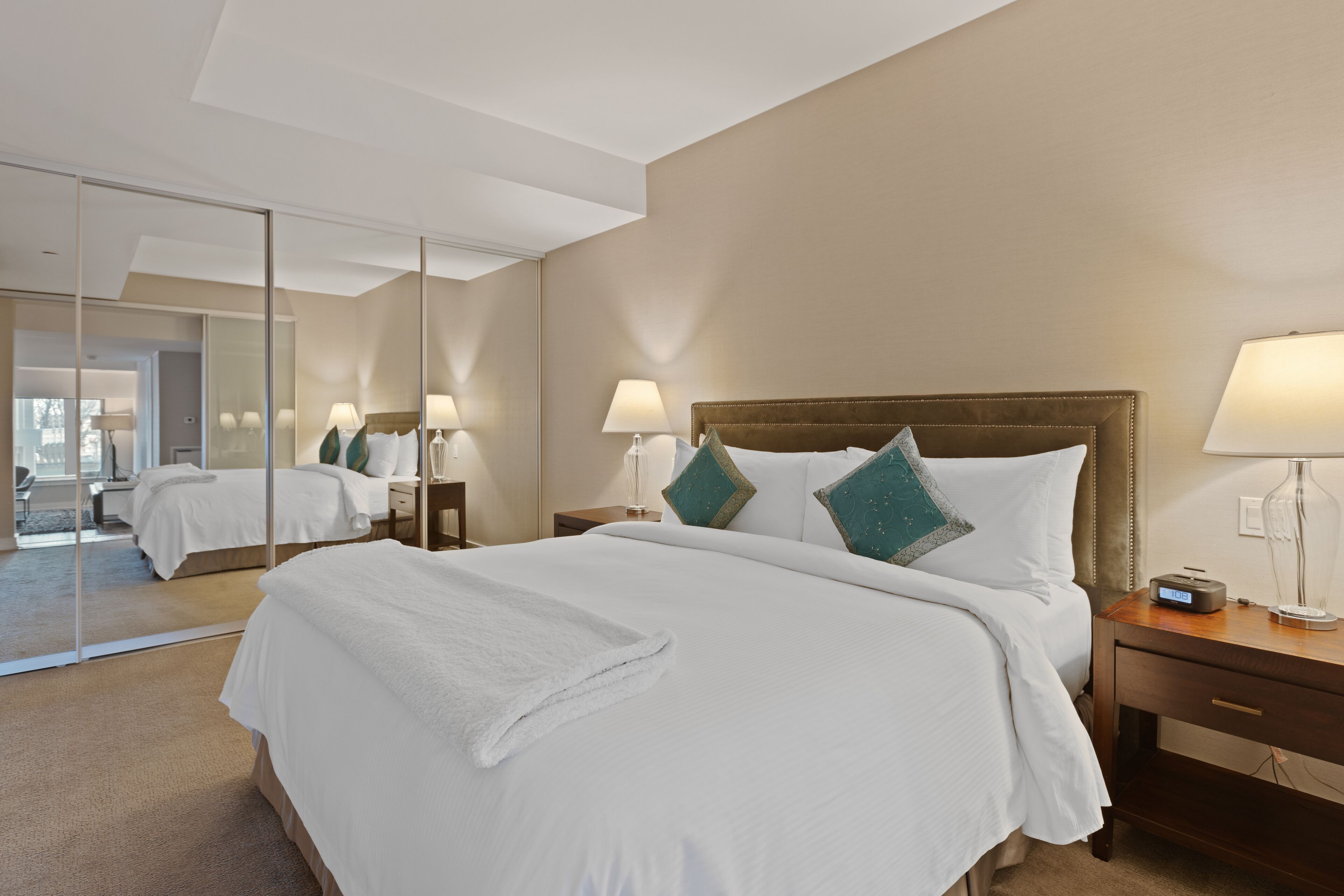 A hotel room with a large bed, two bedside tables, a mirror, and a nightstand.