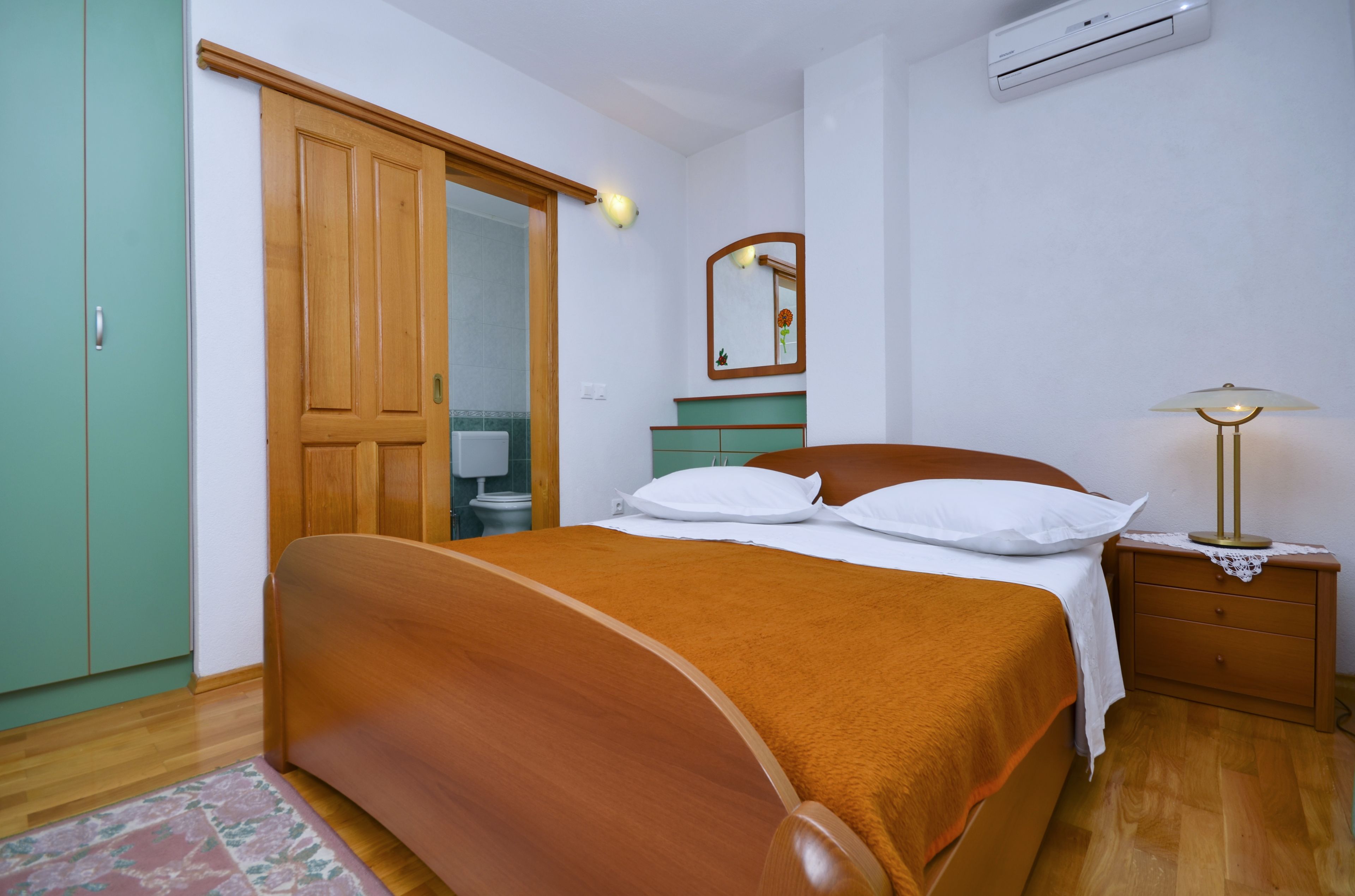 A bedroom with a wooden bed, a nightstand, a mirror, and a wardrobe.