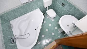 Une salle de bain équipée d’une baignoire, de toilettes et d’un bidet.