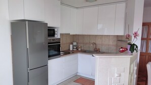 Una cocina moderna con armarios blancos, electrodomésticos de acero inoxidable y una pequeña isla con pileta.