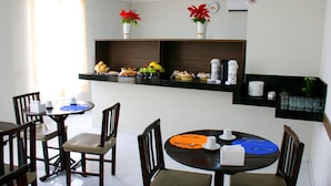 A dining area with two round tables, each with four chairs. There are decorative items on the walls, including potted plants and a clock. - Hotel Belugi (Goiania)