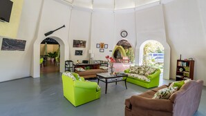 Ein geräumiger Wohnbereich mit grünen und braunen Sofas, einem Couchtisch und einem Bücherregal.