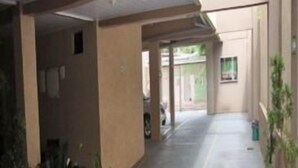 A covered outdoor corridor with potted plants, a concrete floor, and a view of the outside. - Hotel Alves (Goiania)