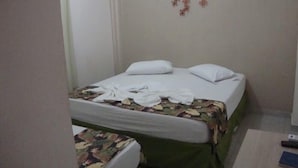 A hotel room with two beds, one with a floral bedspread and the other with a plain white bedspread. There is a wall decoration above the beds and a remote control on the floor. - Hotel Alves (Goiania)