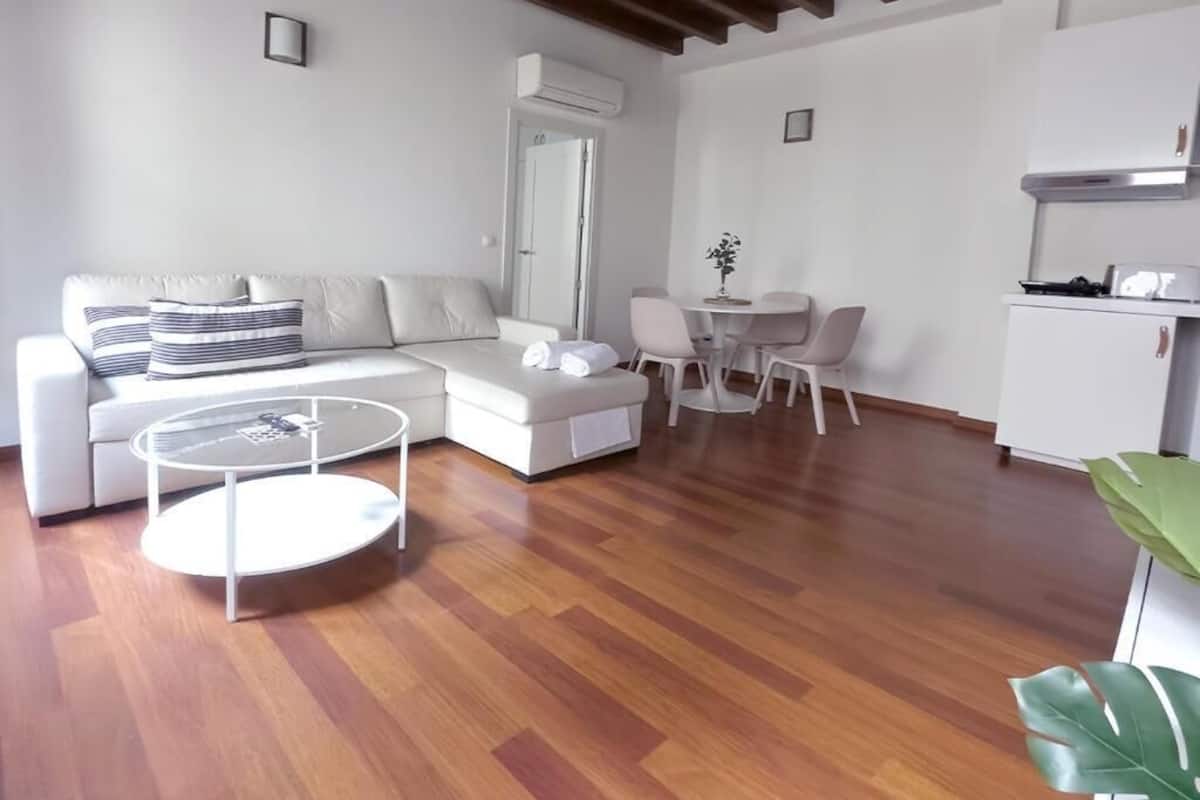 A modern living room with a sofa, a coffee table, and a dining area with chairs.