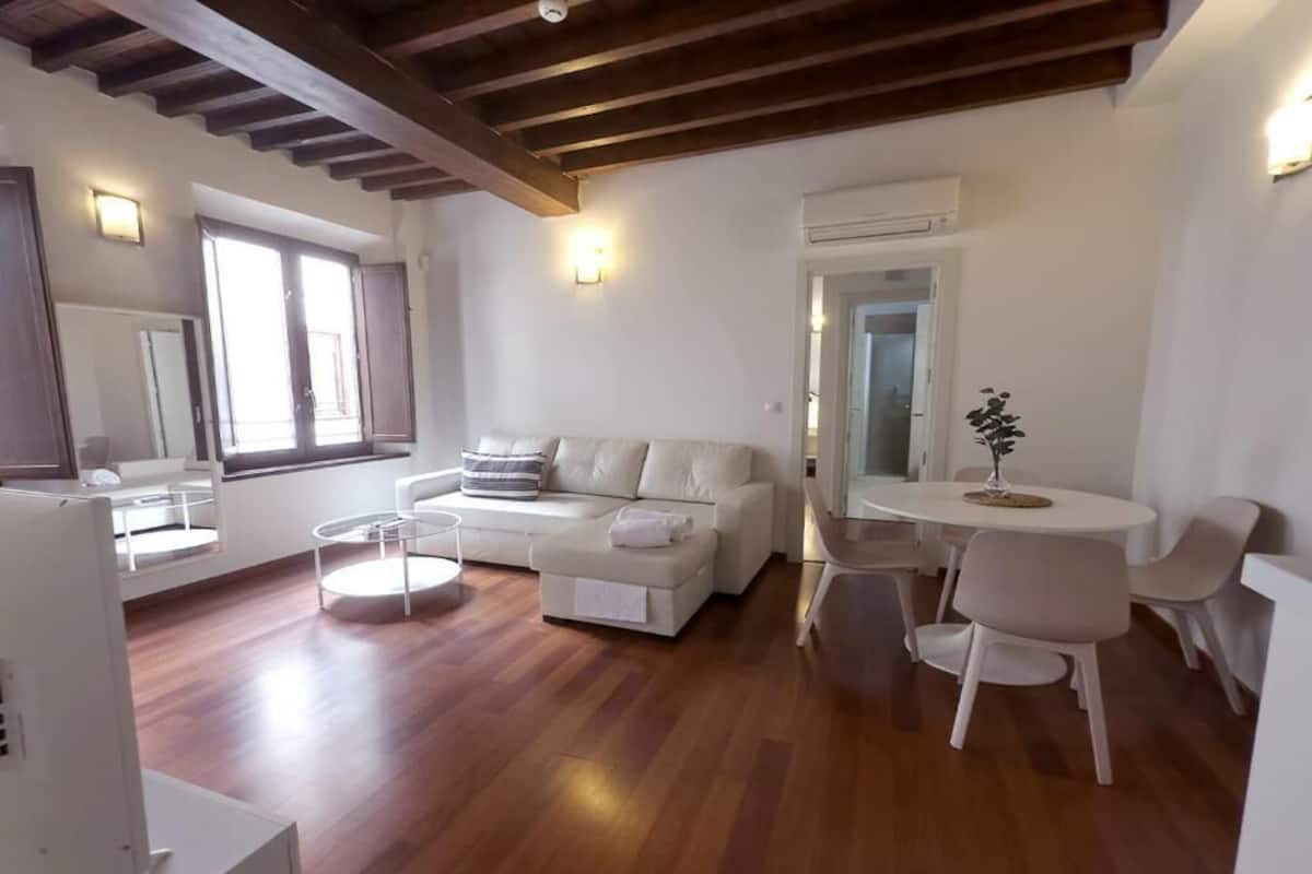 A modern living room with a sofa, coffee table, and dining area.