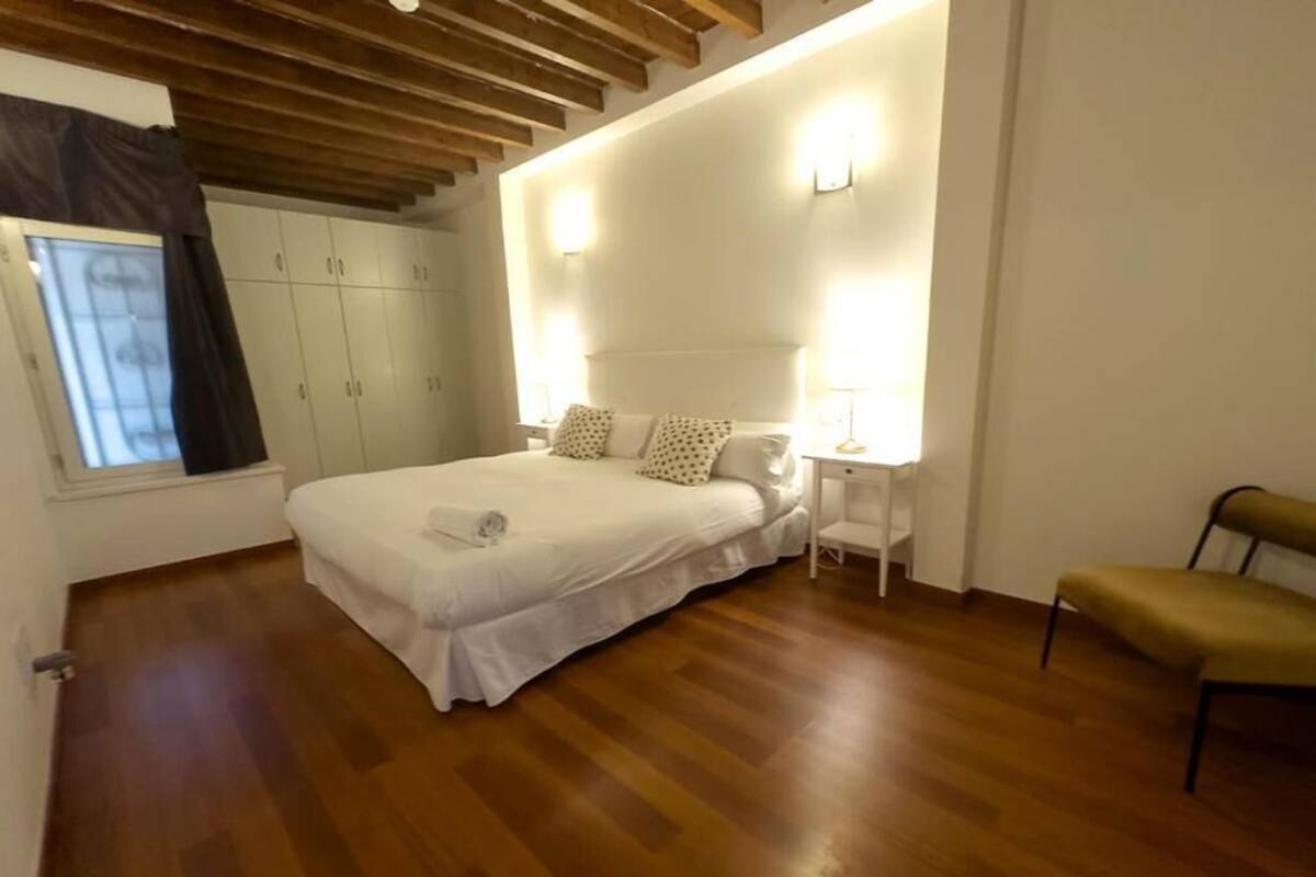 A bedroom with a bed, bedside tables, a chair, and a wardrobe.
