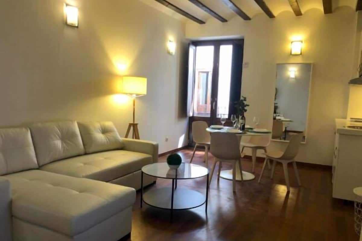 A living room with a sofa, a round coffee table, and a dining area with chairs and a table.
