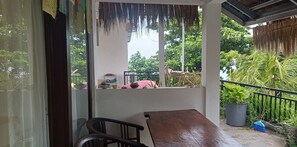 Un balcon avec une table en bois, des chaises et un pot de fleurs.