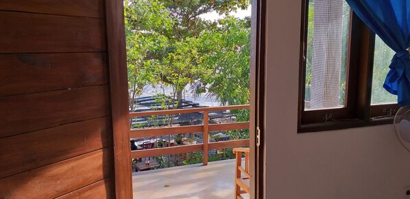 Un balcón de madera con vistas a la vegetación y un edificio al otro lado del agua.