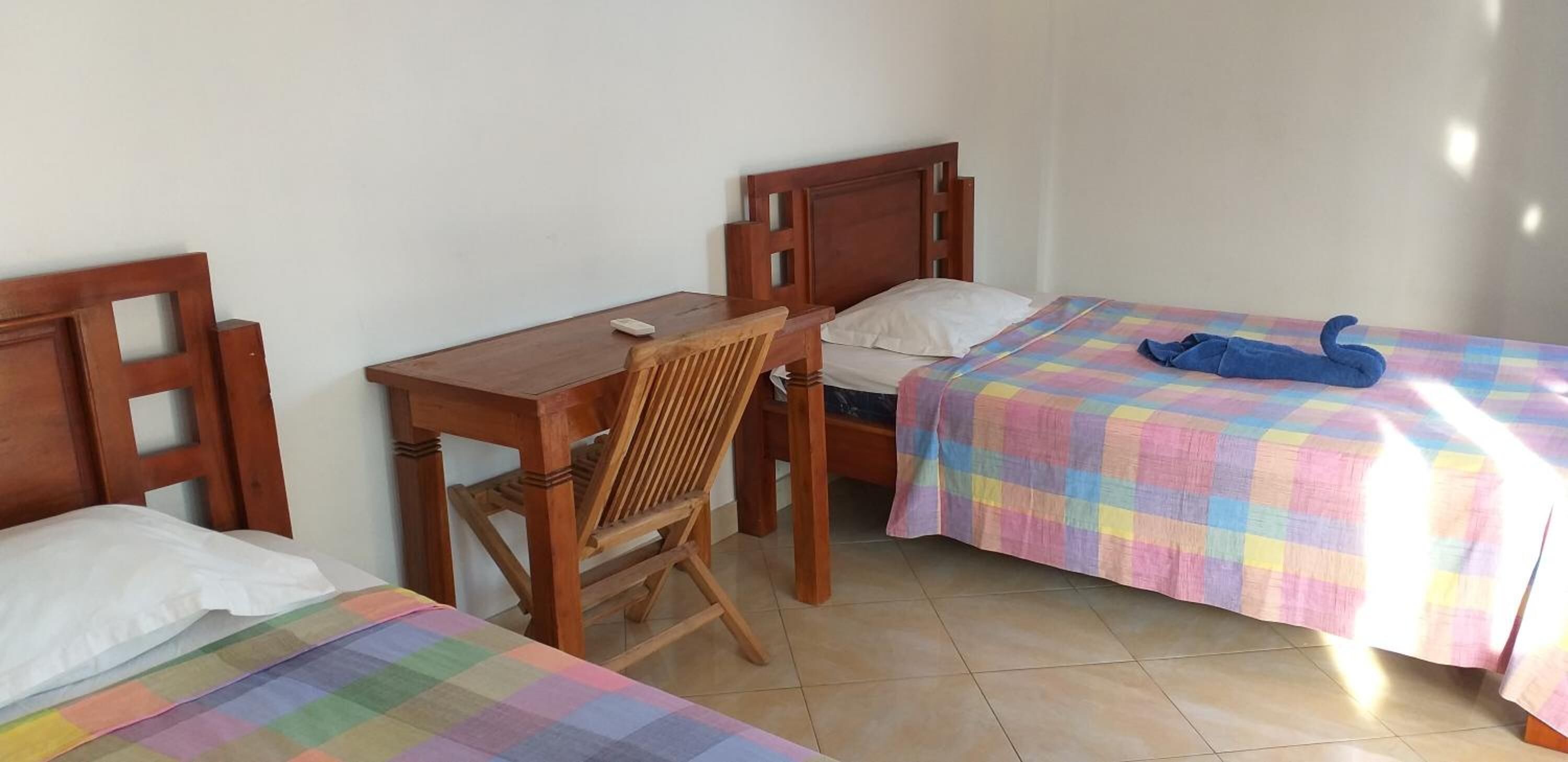 Une chambre avec deux lits simples, un bureau en bois et une chaise.