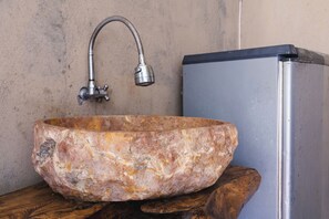 Un bassin en pierre avec un robinet fixé sur une plateforme en bois.