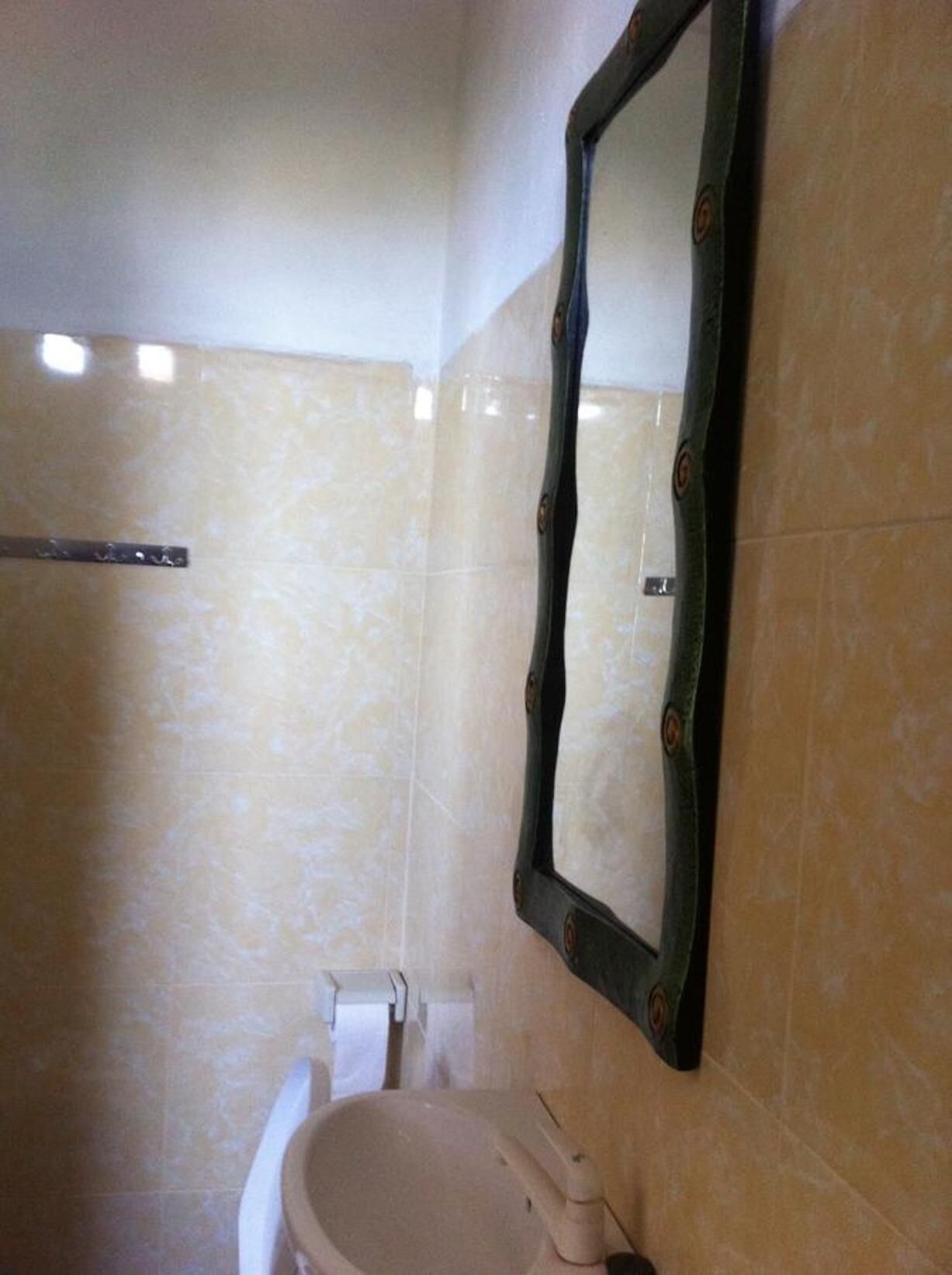 A bathroom with a beige sink, a mirror, and a toilet.
