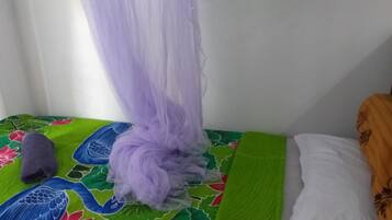 A bed with a colorful bedspread, a purple canopy, and a pillow with a floral pattern.