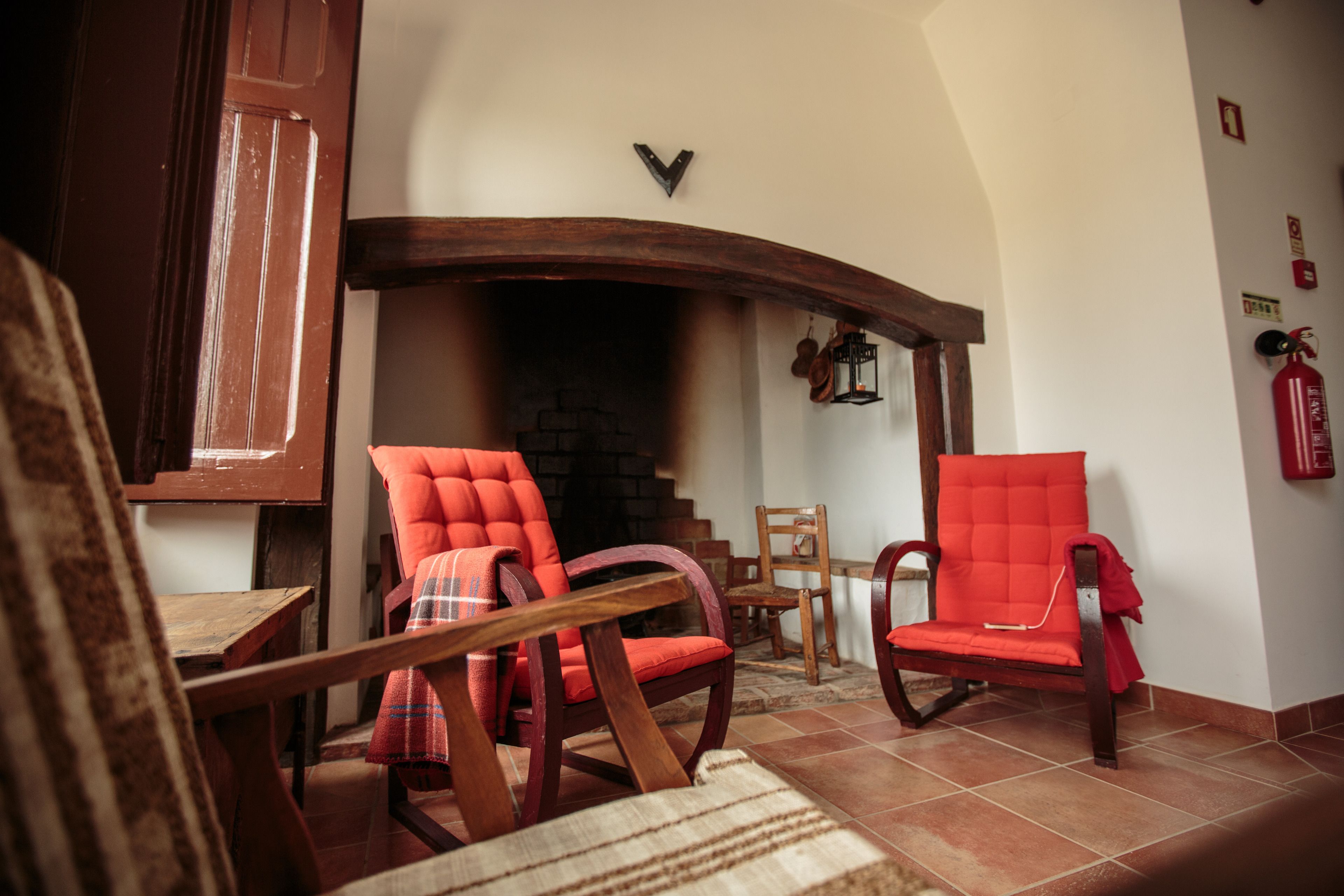 A cozy living room with a fireplace, wooden furniture, and a tiled floor.