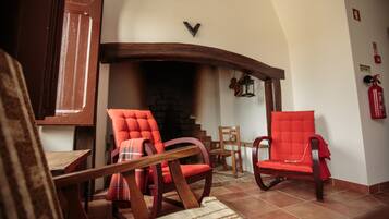 A cozy living room with a fireplace, wooden furniture, and a tiled floor.