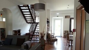 Un vaste espace de vie comprenant un escalier, un canapé et une table à manger.