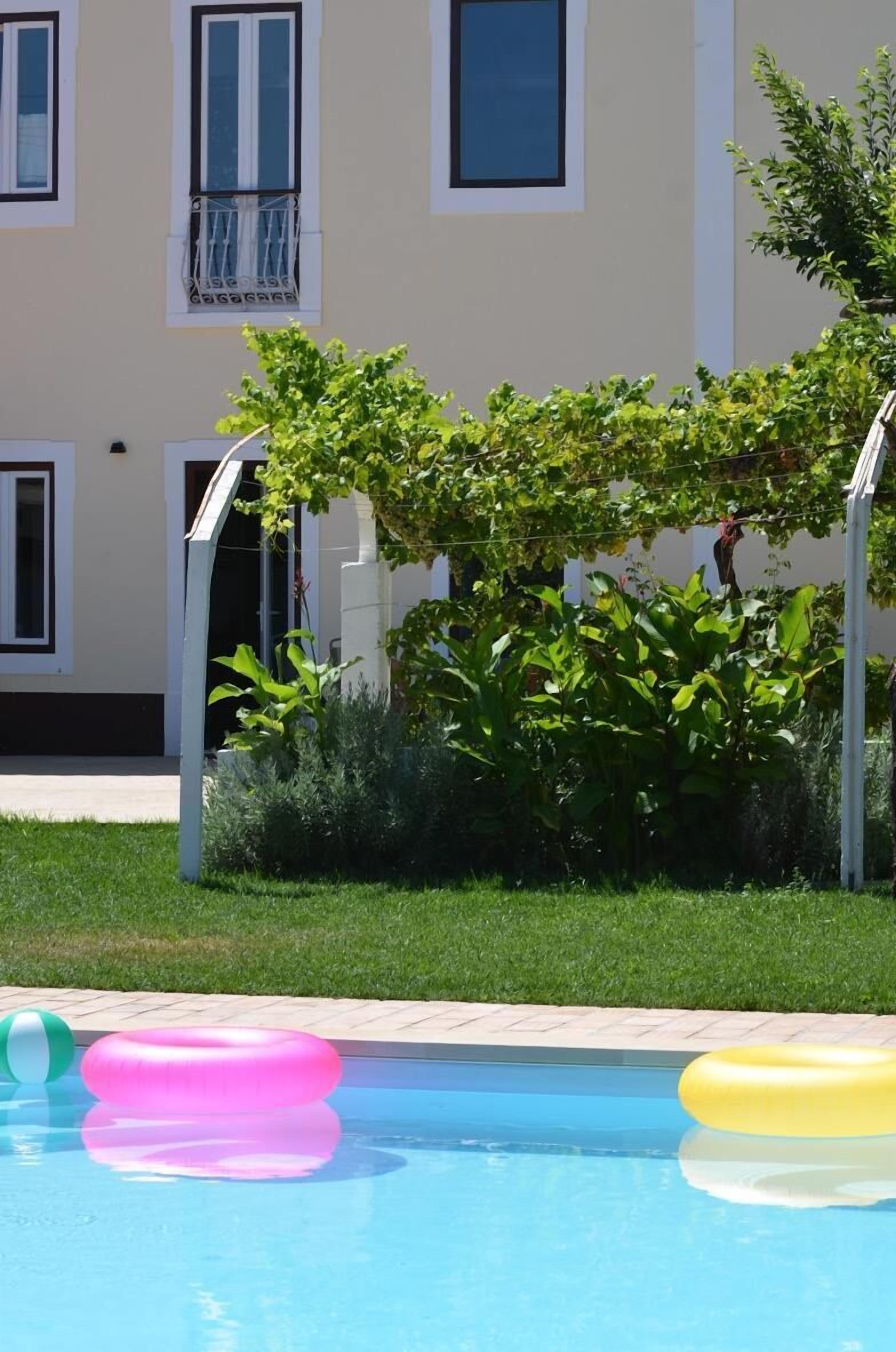 A swimming pool with inflatable rings and a building with balconies in the background.