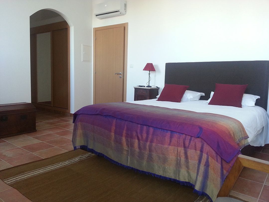 A bedroom with a bed, a nightstand, a lamp, and a wardrobe.
