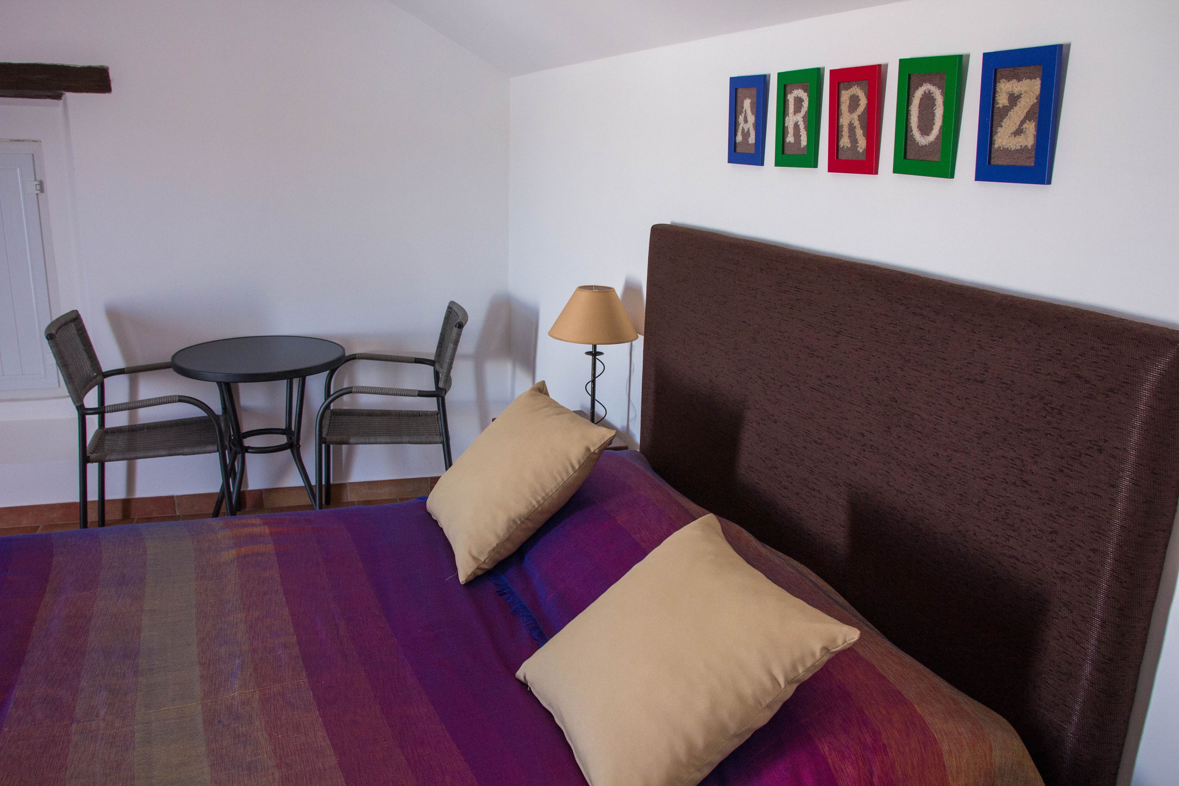 A bedroom with a bed, two chairs, a small round table, and a lamp.