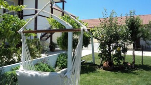 Un hamac dans un jardin, avec un bâtiment en arrière-plan.