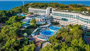 A large resort with multiple swimming pools, a wind turbine, and lush greenery.