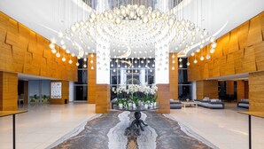 A spacious lobby with a large chandelier, wooden paneling, and a central floral arrangement.