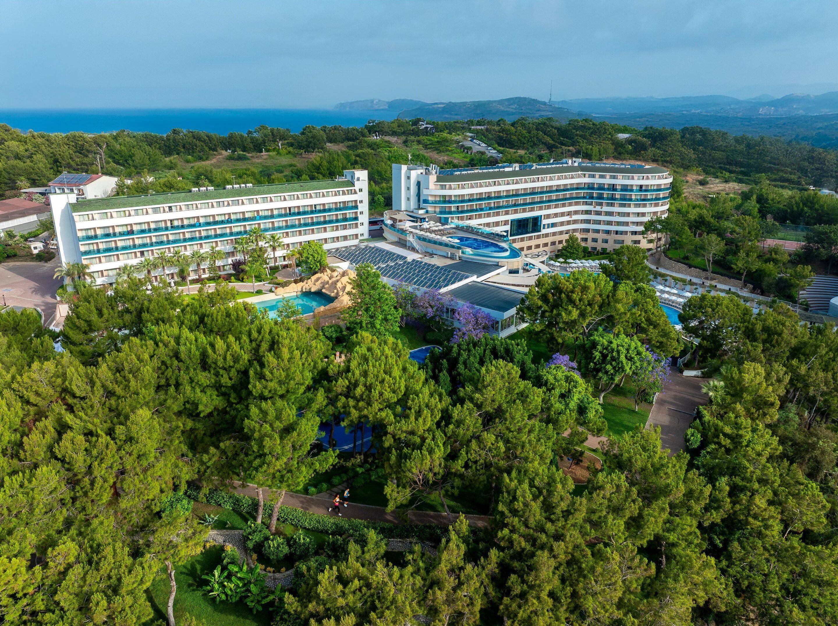 Un hotel con varios pisos, piscina y vistas al mar.