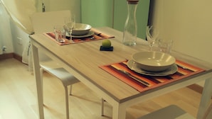 Une table à manger dressée avec des assiettes, des bols, des verres et une bouteille.