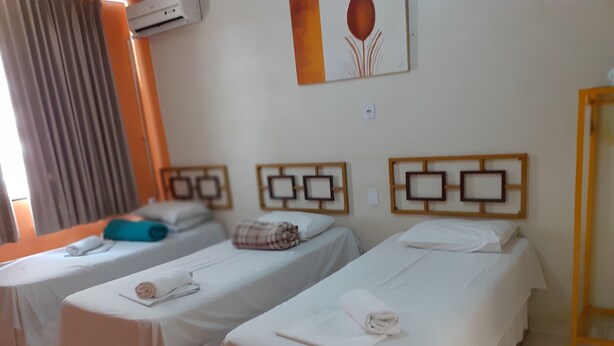 Habitación de hotel con dos camas individuales, una mesita y una silla.