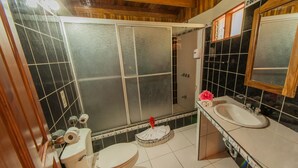 A bathroom with two toilets, a sink, and a shower stall. - Hotel El Atardecer (Monteverde)