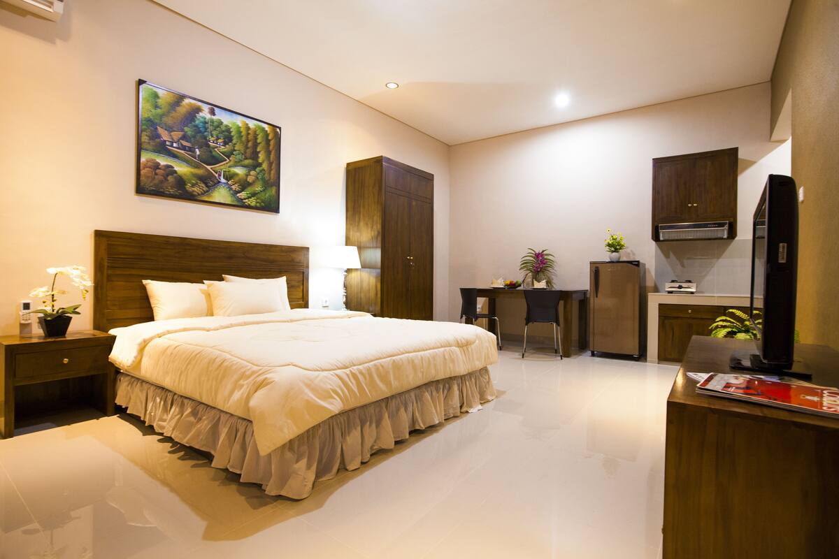 A bedroom with a large bed, a desk, a chair, and a television.