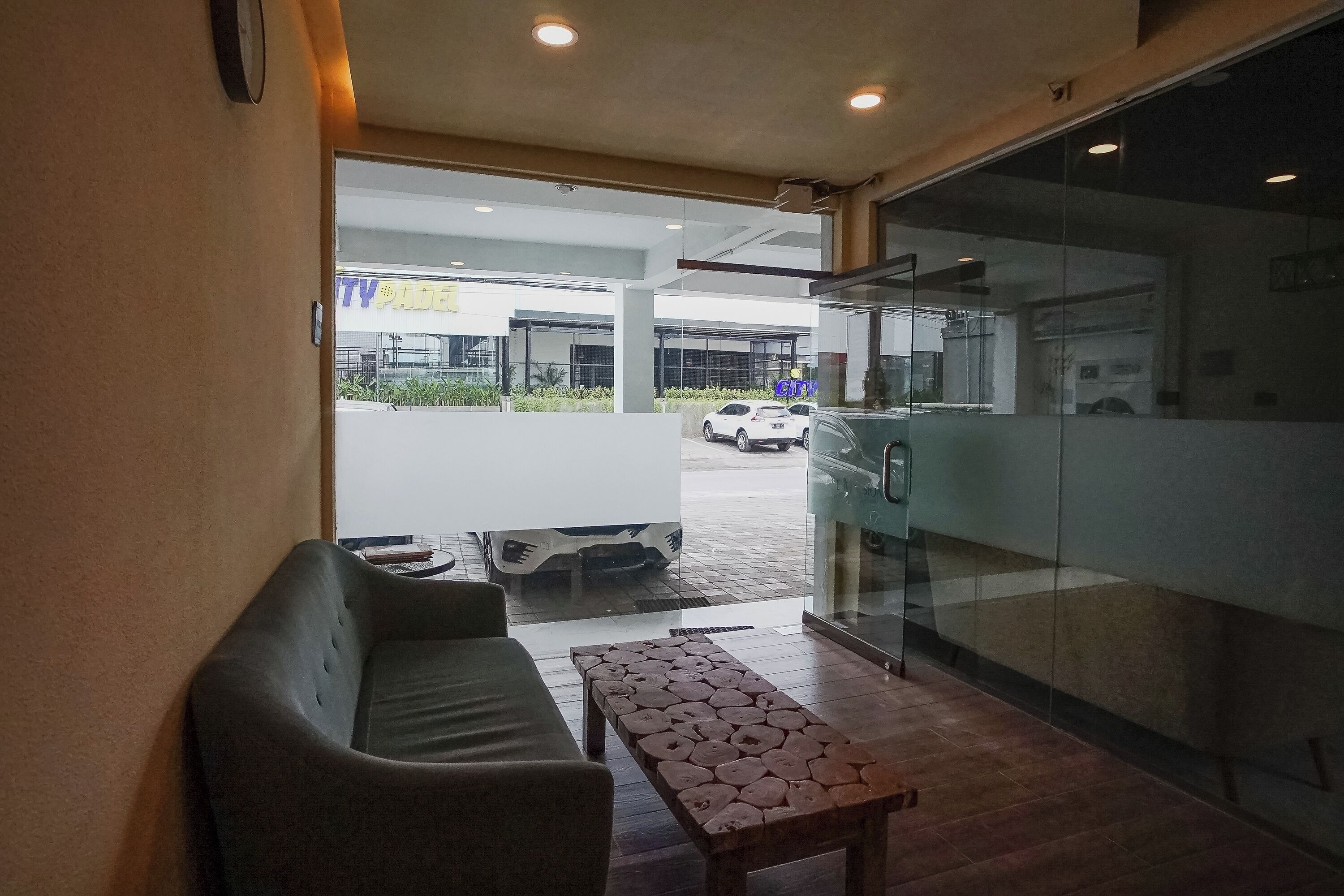 A modern hotel lobby with a sofa, a wooden table, and a glass partition.